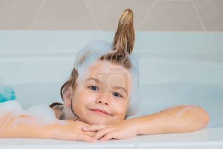 Foto de Baño de niños. Feliz chico divertido bañado en el baño. Niño en la ducha. Los niños se enfrentan en el baño con espuma. Retrato de bebé bañándose en un baño lleno de espuma - Imagen libre de derechos