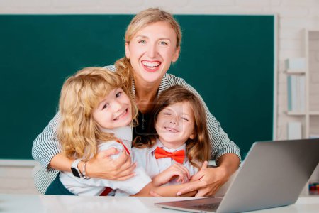 Photo for Happy school kids and teacher learning study in class. Teacher helping child students pupils from elementary school in classroom - Royalty Free Image