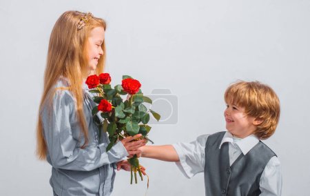 Téléchargez les photos : Petit garçon avec une rose pour sa petite amie adolescente, des enfants romantiques, isolés sur fond blanc. Concept d'amour - en image libre de droit