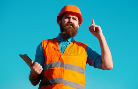 Téléchargez les photos : Travailleur de construction dans le casque posant sur le chantier de construction. Concept de construction et de chantier - en image libre de droit