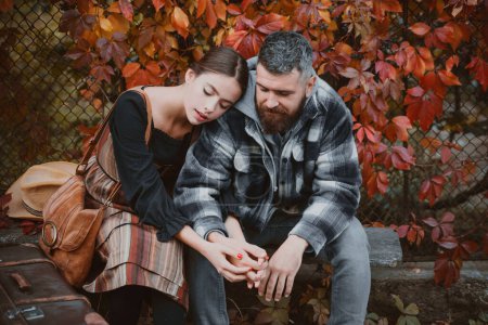 Photo for Girl and bearded guy or happy lovers on a date hold hands. Dating and autumn love concept. Couple in love sit near wall with ivy leaves. Hipster romantic couple in vintage outfit - Royalty Free Image