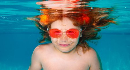 Téléchargez les photos : Les enfants d'été font face. L'enfant sous-marin nage dans la piscine, nage en bonne santé et s'amuse sous l'eau. Enfants sous-marins. Vacances d'été avec enfant - en image libre de droit