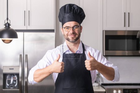 Photo for Happy baker with thumb up. Handsome man chef in uniform cooking in the kitchen. Restaurant menu concept. Hispanic man in baker uniform. Cooking and culinary - Royalty Free Image