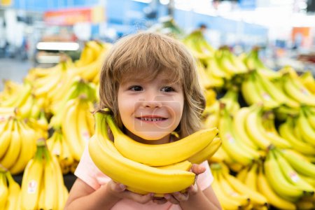 Téléchargez les photos : Portrait d'enfant avec banane achetant de la nourriture à l'épicerie. Des gosses drôles. Ventes et achats. Il achète des produits au supermarché. Supermarché et épicerie. Remise, concept de vente - en image libre de droit