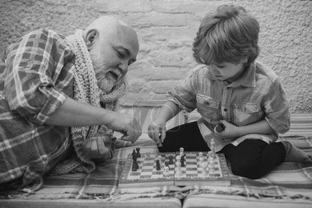 Foto de Generaciones. Jaque mate. Pasatiempos de ajedrez - abuelo con nieto en un ajedrez de juego - Imagen libre de derechos