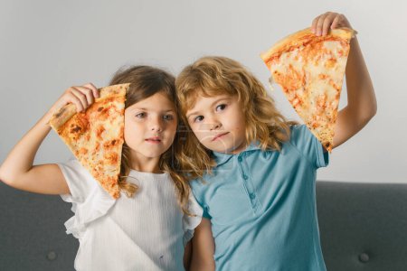 Photo for Funny kids eating pizza. Cute kids holding pizza slice near face - Royalty Free Image