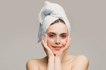 Foto de Mujer aplicando parches en los ojos. Retrato belleza chica con toalla en la cabeza - Imagen libre de derechos