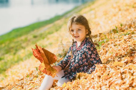 Foto de Niña linda jugando con hojas de otoño. La caída del arce deja un fondo natural. Caída fondo exterior - Imagen libre de derechos