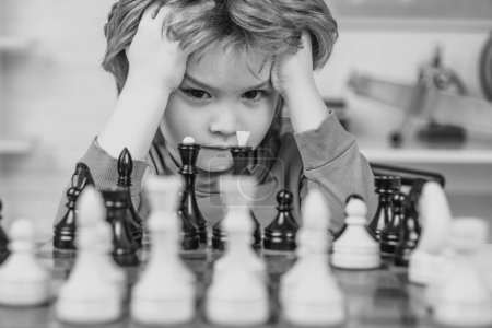 Téléchargez les photos : Échecs, succès et victoire. Intelligent concentré et pensant enfant tout en jouant aux échecs. Jeux éducatifs pour enfants, développement précoce de l'enfant - en image libre de droit