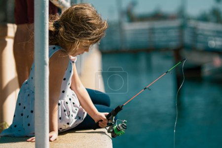 Foto de Focused, serious, little children girl catch a fish by a fishing rod - Imagen libre de derechos