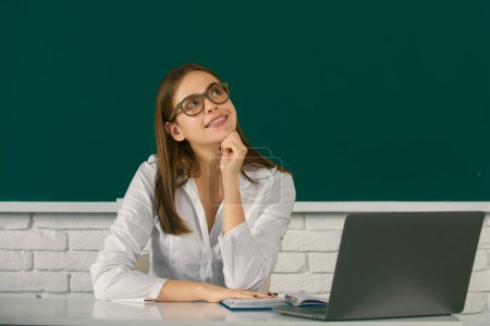 Photo for Portrait of dreaming young college student in classroom on blackboard background, copy space - Royalty Free Image