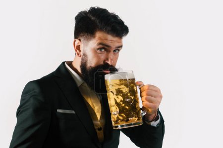 Téléchargez les photos : Portrait d'un bel homme barbu dégustant une bière artisanale. Un bel homme élégant en costume noir qui boit de la bière. gay boire bière lager - en image libre de droit