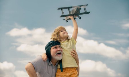 Photo for Grandfather and son enjoying play with plane together on blue sky. Cute child with granddad playing outdoor. Generations ages - Royalty Free Image
