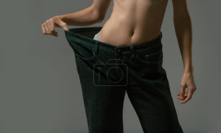 Téléchargez les photos : Thin woman in big pants, weight loss concepts. Slim girl with oversized big trousers. Woman weight loss. Woman with slim body after dieting - en image libre de droit