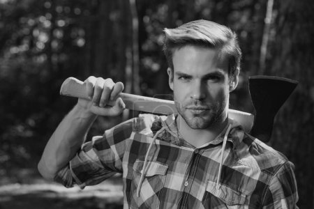 Photo for Lumberjack on serious face carries axe on shoulder - Royalty Free Image