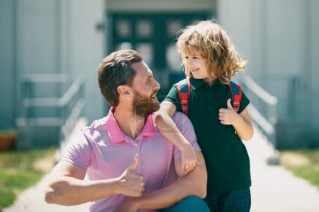 Foto de El chico de la escuela va a la escuela con su padre. Cara feliz. Pulgares hacia arriba signo - Imagen libre de derechos