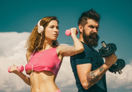Photo for Strong man and sexy woman working out with dumbbells on sky background. Couple working out with dumbbell weights. Attractive woman and handsome muscular man are training outdoors - Royalty Free Image