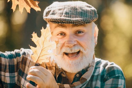Photo for Senior citizen stroll in a park in autumn. Old man alone in autumn park. Elderly old man on autumn background - face portrait close up - Royalty Free Image
