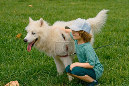 Téléchargez les photos : Joyeux enfant avec chien sur gras. Portrait enfants garçon avec animal de compagnie jouer à l'extérieur - en image libre de droit