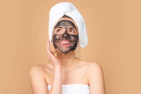 Téléchargez les photos : Woman with charcoal facial mud mask on face. Cosmetic procedure. Beauty spa and cosmetology. Spa woman applying gray facial clay mask. Beauty treatments - en image libre de droit