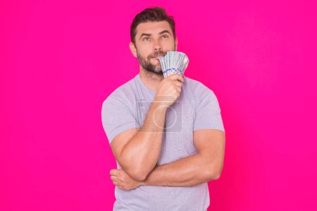Foto de Hombre de negocios en camiseta con billetes de dinero en efectivo aislados en el fondo del estudio rosa. Billete de cien dólares, concepto financiero - Imagen libre de derechos