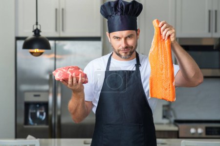Photo for Health, natural protein. Handsome man in kitchen cooking fish and meat, salmon and beef in the kitchen. Healthy food concept. Healthy diet, meat protein. Raw fish and meat - Royalty Free Image