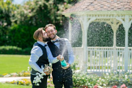 Foto de Emocionado pareja gay abierto champán y besos en el día de la boda. Pareja gay romántica y sensual. gay novios juntos en boda día - Imagen libre de derechos