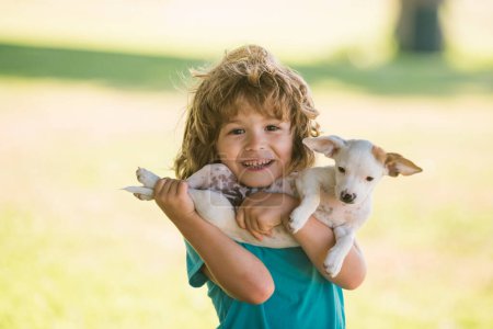 Téléchargez les photos : Garçon enfant avec chien relaxant sur la nature. Charmant mignon enfant embrasse son chien de compagnie - en image libre de droit