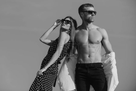 Foto de Fashion girl and guy in outlet clothes posing on a blue sky background. Lovers and valentines day - Imagen libre de derechos