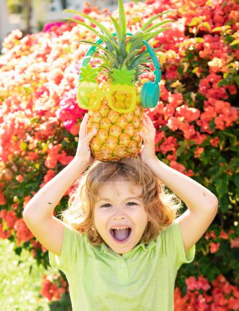 Photo for Little blonde kid hugging pineapple on nature background. Childhood, healthy nutrition, advertising. Close up kids funny face, copy space - Royalty Free Image