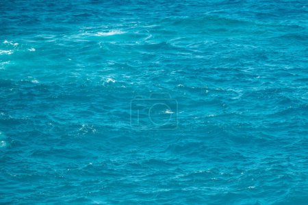 Téléchargez les photos : Texture calme de la surface de l'eau de mer avec éclaboussures et vagues. Nature abstraite. Contexte de la surface de l'eau de l'océan aqua - en image libre de droit