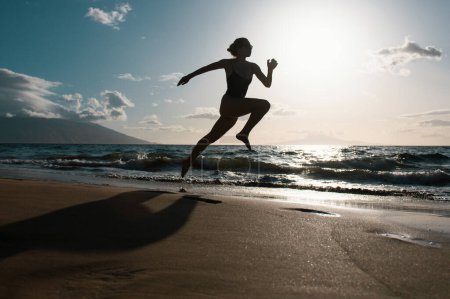 Photo for Silhouette of runner woman exercising in running sprint workout at beach jogging, healthy outdoors activity - Royalty Free Image