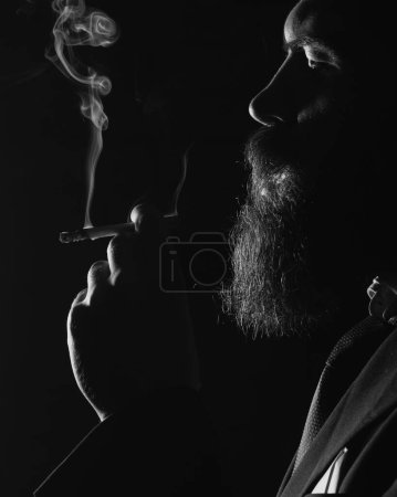 Téléchargez les photos : Un fumeur de cigarettes. Fumée sur fond noir. Fumée de cigarette sur fond noir. Homme d'affaires fumeur. Dépendance à la nicotine de cigarette - en image libre de droit