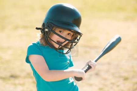 Téléchargez les photos : Un gamin drôle tenant une batte de baseball. Pitcher enfant sur le point de jeter dans le baseball des jeunes - en image libre de droit