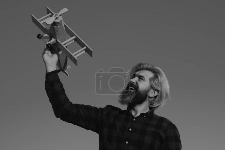 Foto de Man play with toy plane. Bearded crazy man with a wooden airplane. Dreams of flying. Travel concept - Imagen libre de derechos