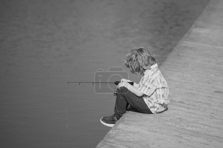 Foto de Niño dedicado a pasatiempos de pesca, sostiene una caña de pescar. Estilo de vida de verano. Niños pescando en fin de semana, espacio de copia - Imagen libre de derechos