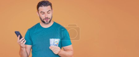 Foto de Hombre de negocios en camiseta con billetes de dinero en efectivo aislados en el fondo amarillo del estudio. Billete de cien dólares, concepto financiero - Imagen libre de derechos