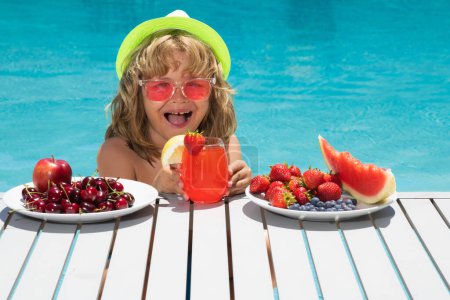 Photo for Child eating fruits near swimming pool during summer holidays. Healthy kids and summer vacation. Kids eat fruit. Healthy fruits for children. Summer vacation with children - Royalty Free Image