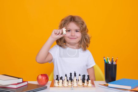 Photo for Chess for intelligent kid. Child genius, smart pupil playing logic board game. Clever school boy thinking about chess. Little chess player on yellow isolated studio background - Royalty Free Image