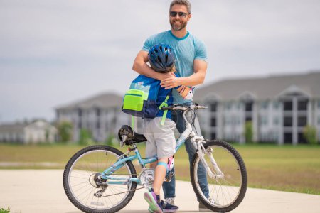 Photo for Little kid learning to ride bicycle with father in park. Father teaching son cycling. Father and son learning to ride a bicycle at Fathers day. Father support and helping son. Child care - Royalty Free Image