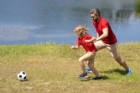 Photo for Father and son playing football together. Dad with kid spend hours practicing passing and kicking soccer ball. Dad and son playing football together on green meadow. Father and son on football pitch - Royalty Free Image