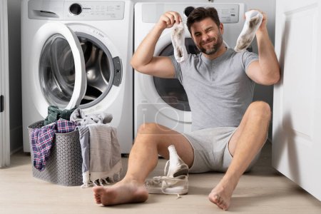Photo for Man with clothes near washing machine. Laundry cleaning. Housework, homework, male housekeeper. Husband man doing laundry at home. Washer and dryer at home - Royalty Free Image