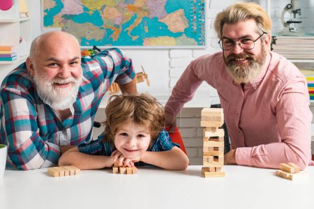 Foto de Tres generaciones de hombres activos jugando en el salón. Jenga juego en casa - Imagen libre de derechos