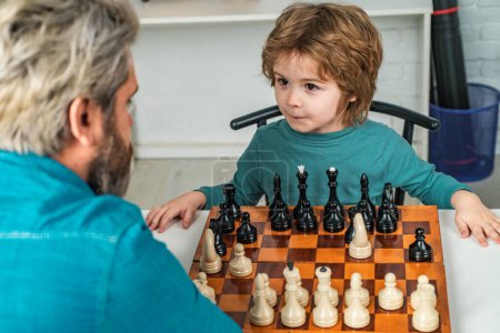 Photo for Intelligent kids. Family holiday and togetherness. Cute boy developing chess strategy. Man teacher play chess with preschooler child - Royalty Free Image
