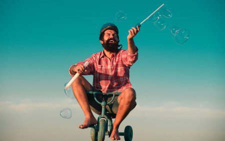 Foto de Memoria de la infancia. Retrato de un hombre barbudo como un hipster loco divirtiéndose con la bicicleta al aire libre - Imagen libre de derechos