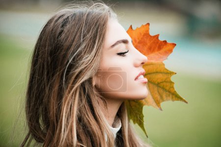Photo for Autumn beauty. Close up photo of fashion woman with fall maple leaf outdoors - Royalty Free Image