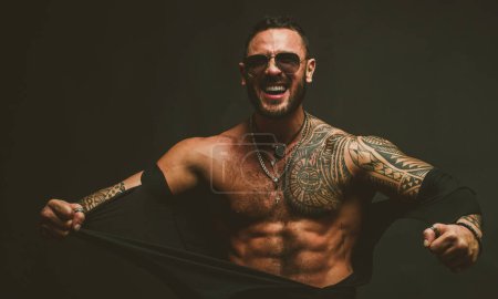 Photo for Furious man isolated on black. Muscular guy with sexy torso ripped shirt - Royalty Free Image
