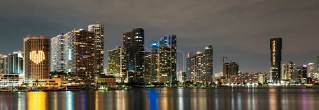 Foto de Panorama del atardecer de Miami con coloridos edificios comerciales y residenciales iluminados y puente en la bahía de Biscayne. skyline de Miami en la bahía de Biscayne, fondos nocturnos de la ciudad - Imagen libre de derechos