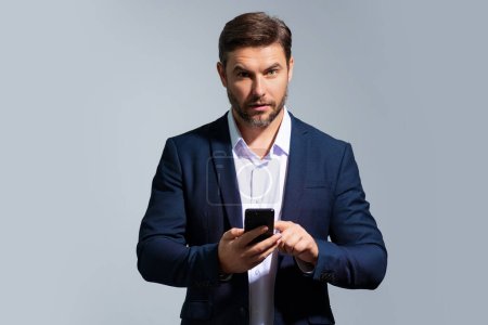Photo for Business man in suit watching on mobile phone. Handsome man wearing formal wear using smart phone, type sms message. Social network. Handsome businessman using mobile phone, talking on phone - Royalty Free Image