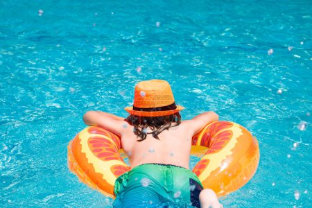 Foto de Niño nadando con anillo flotante en la piscina. Vacaciones de verano para niños. Niño feliz con anillo inflable en la piscina - Imagen libre de derechos